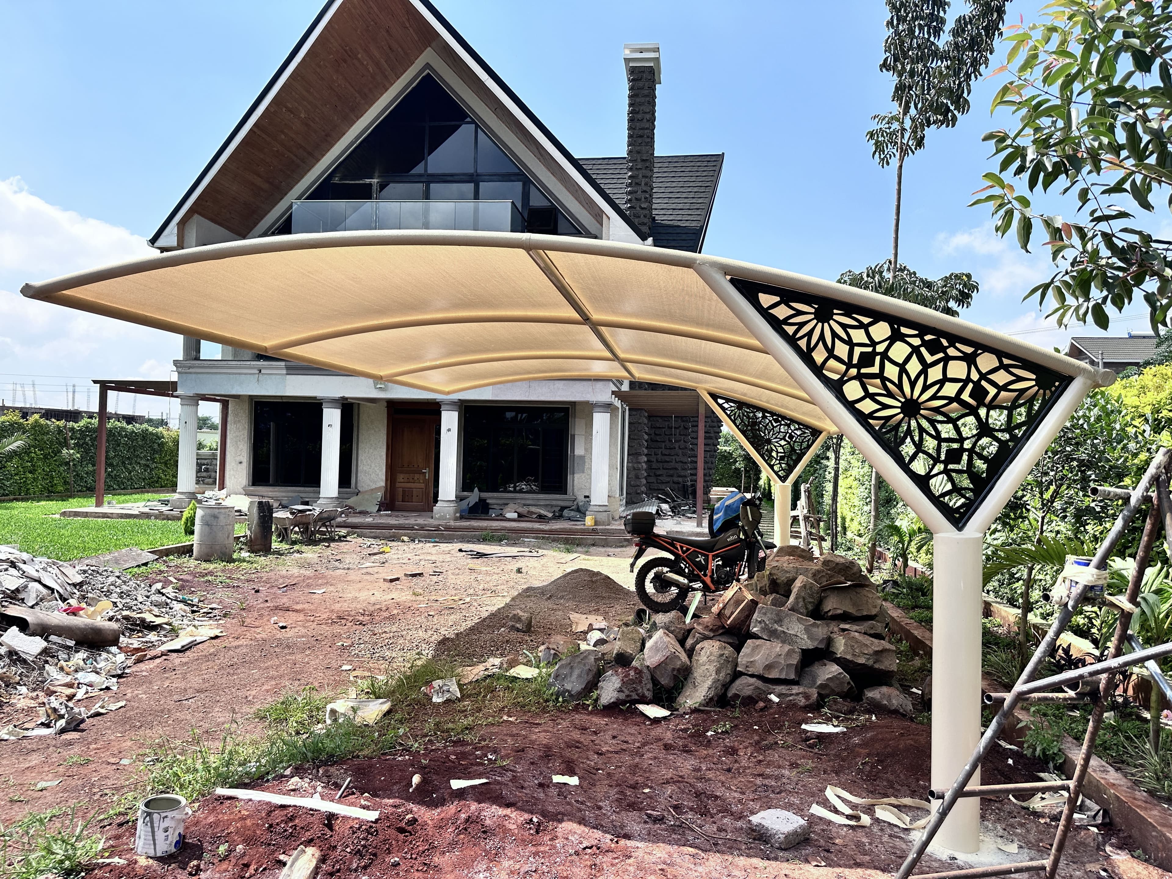 Curved cantilever car parking shade with decorative laser-cut panel installed in Kenya